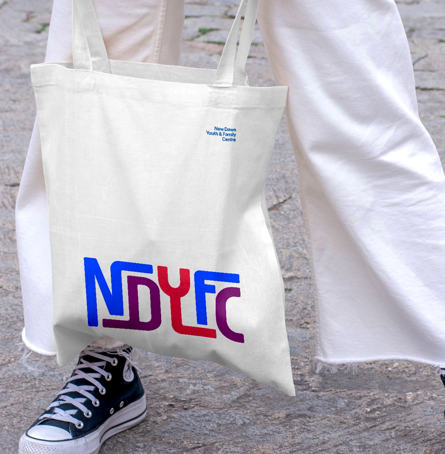 White canvas tote bag displaying the colourful New Dawn Youth and Family Centre logo.