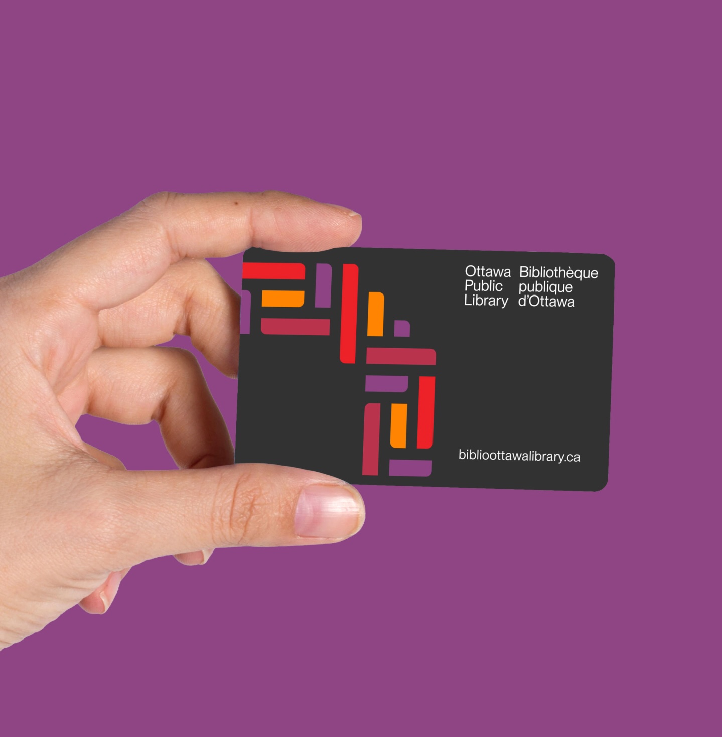 Hand holding Ottawa Public Library's new library cards featuring new logo created by Intent